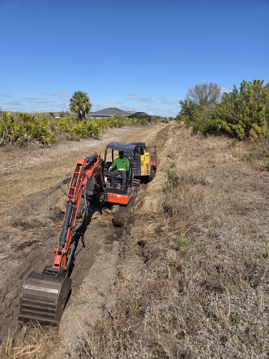 Excavator digging years of silt and growth out of a neglected drainage canal