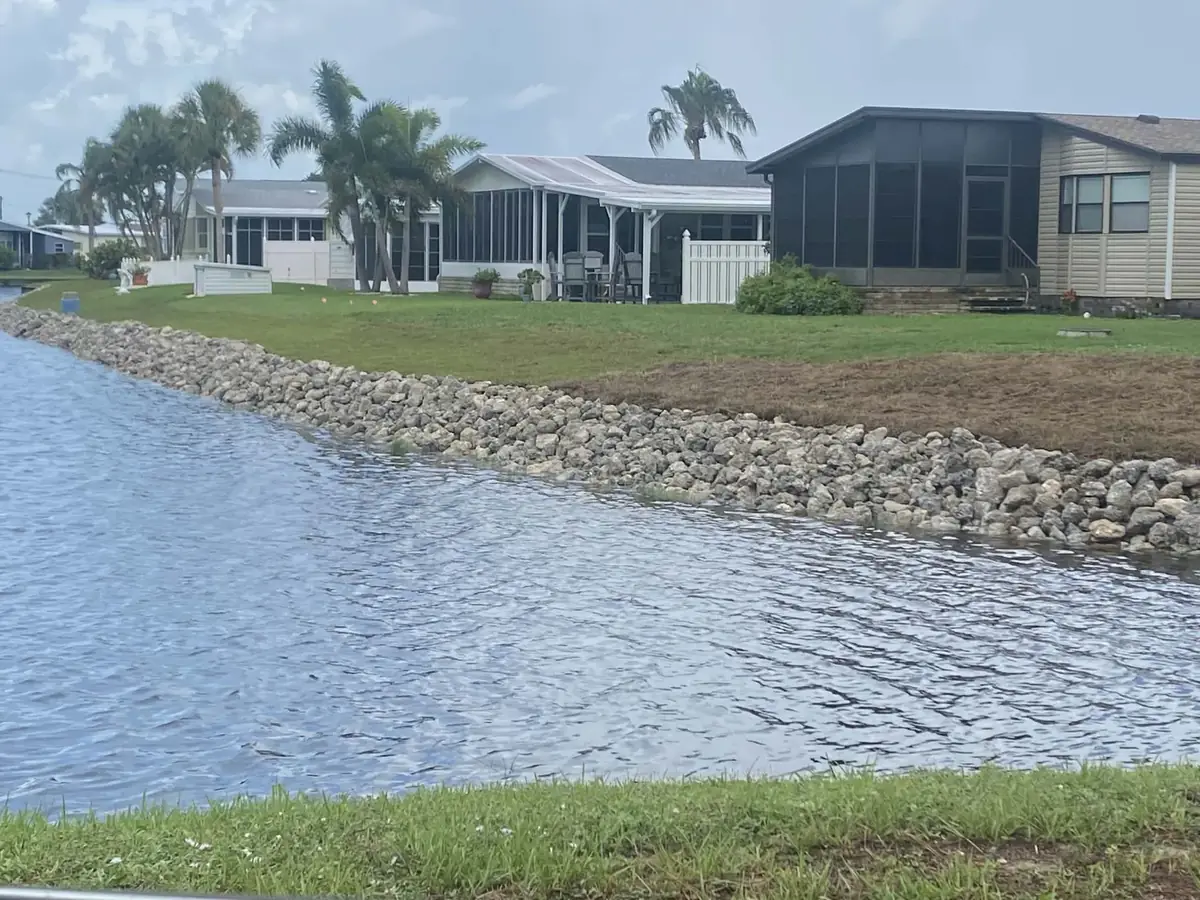 Rock lined shoreline on a community lake behind homes with screened lanais and palms